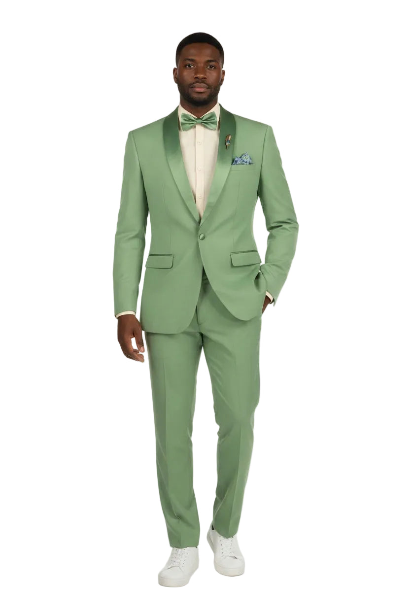 A man modeling a light sage green two-piece suit with satin shawl lapels, a matching green bow tie, a cream dress shirt, and white sneakers against a plain white studio background.