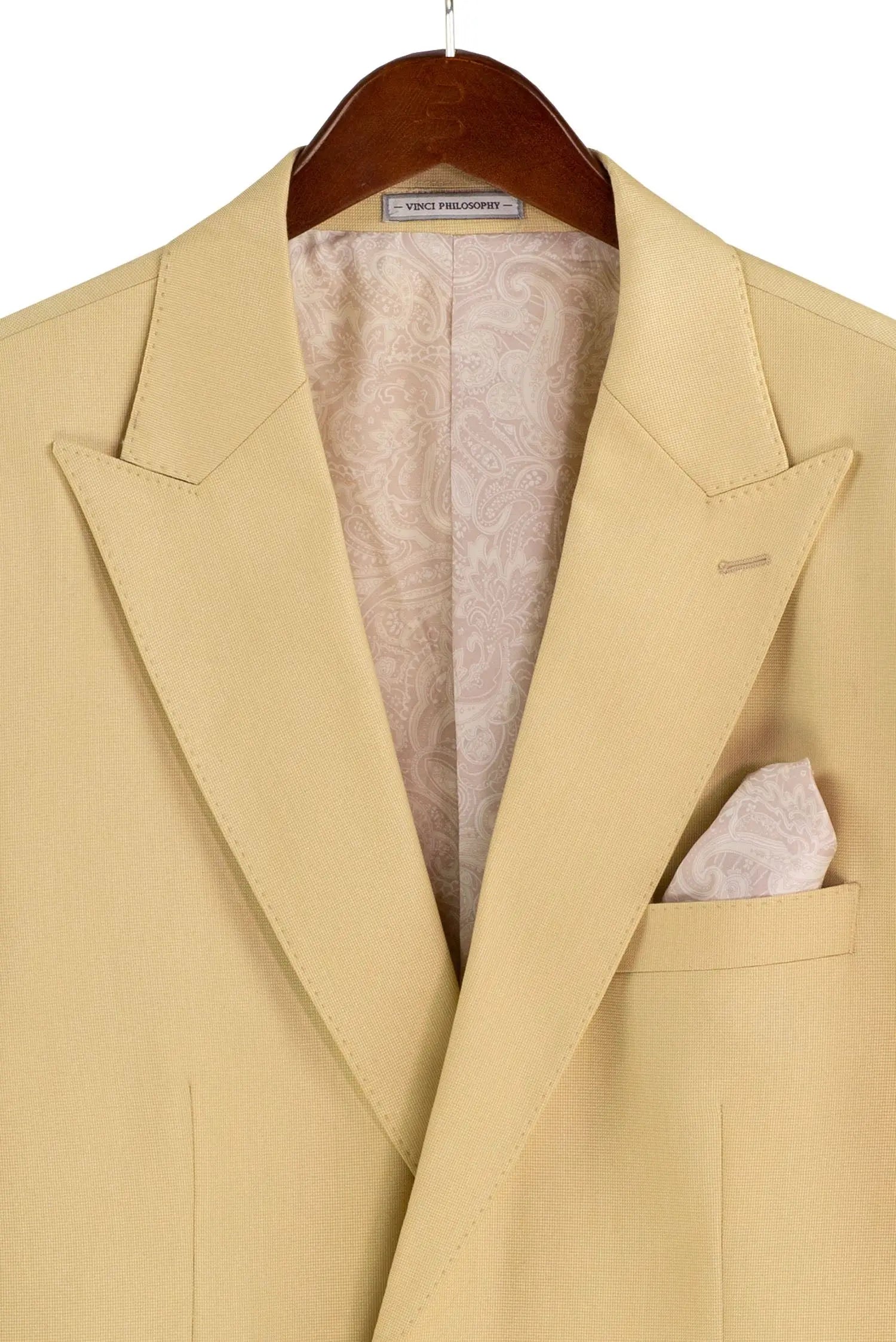 Beige suit jacket on a hanger with a white shirt and pocket square.