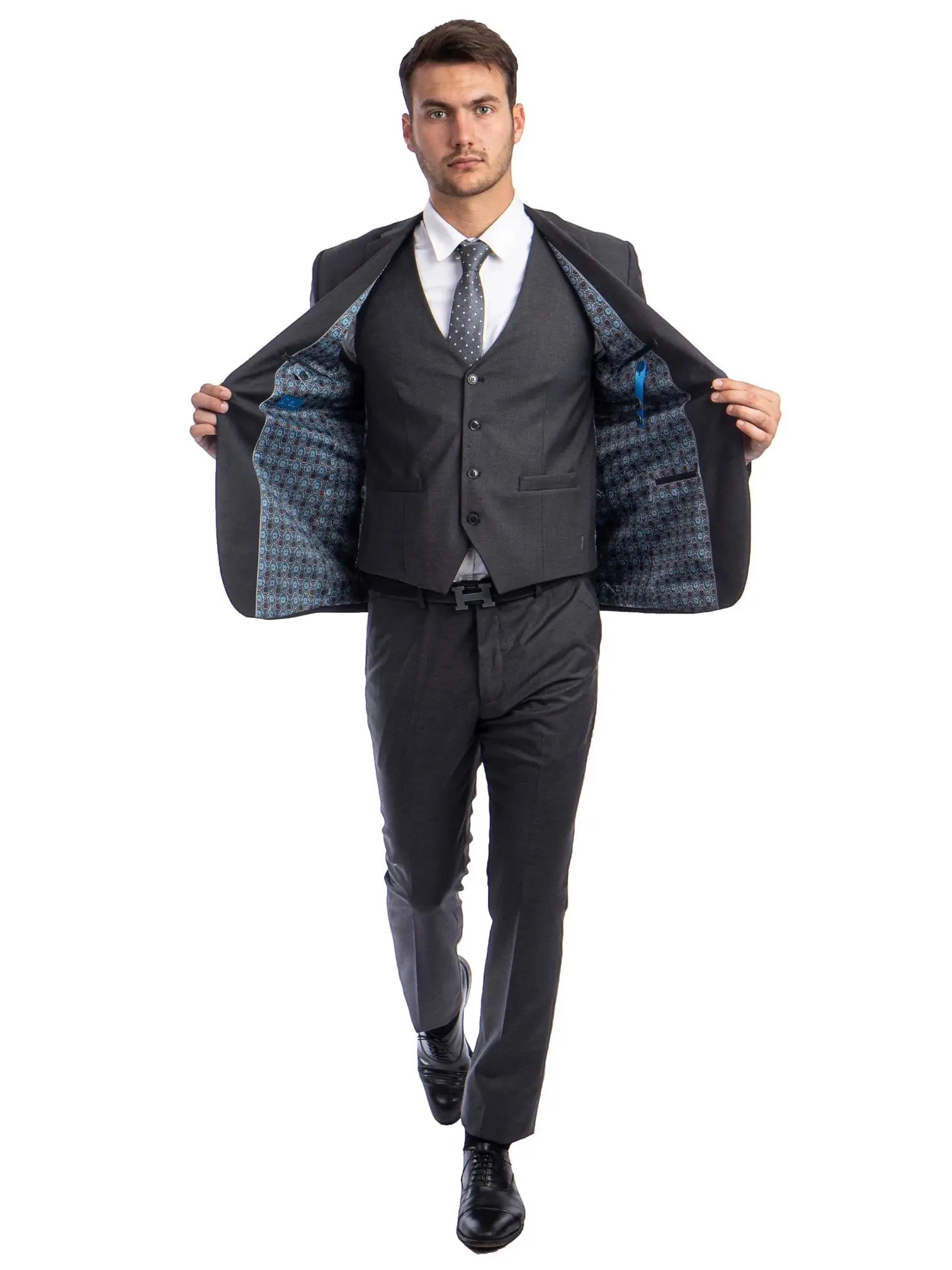 A man wearing a M & R Clothing charcoal grey skinny-fit 3-piece suit with a patterned lining, white shirt, and tie.