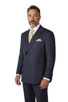 A man wearing a navy blue double-breasted pinstripe suit, a white dress shirt, and a yellow tie, standing against a light gray studio background.