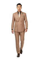 A man modeling a tan double-breasted suit with a brown shirt, beige patterned tie, and brown dress shoes against a plain white background.