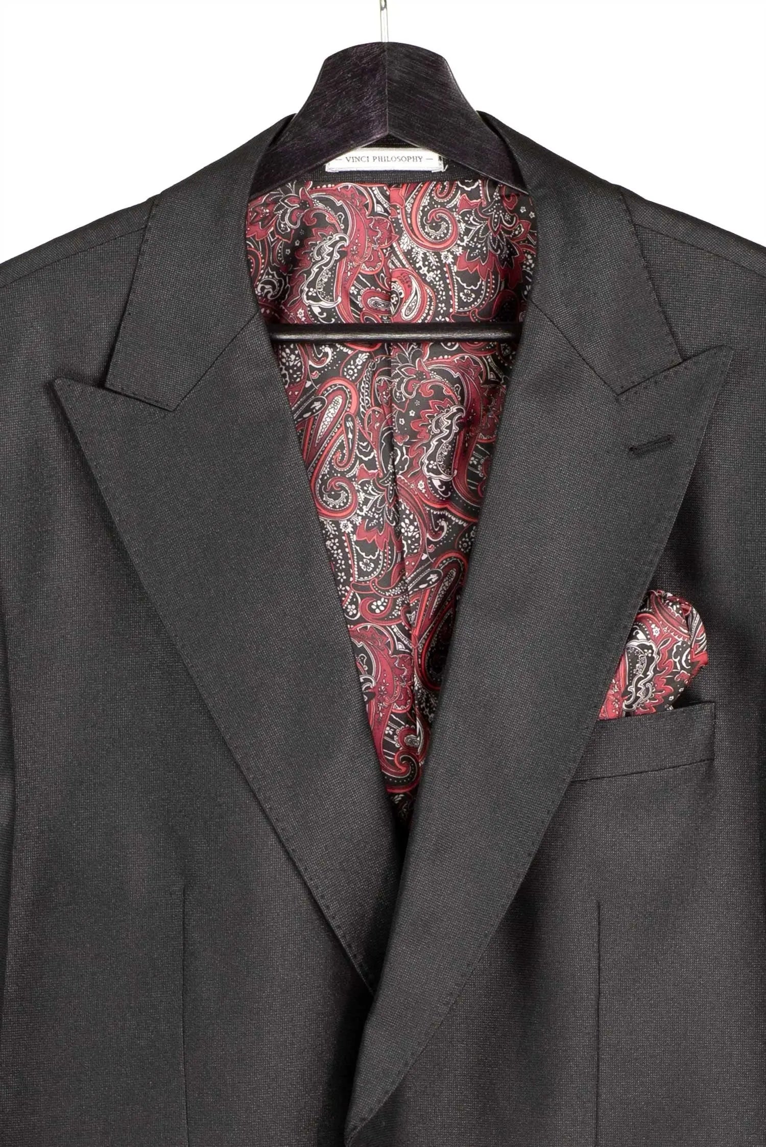 A dark charcoal gray suit jacket displayed on a black hanger, featuring a matching red, black, and white paisley patterned dress shirt and pocket square in the breast pocket.