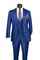A men's three-piece suit in a vibrant royal blue, displayed on a black mannequin torso. The suit includes a jacket, matching vest, and trousers, styled with a white dress shirt, a patterned paisley tie, and a matching pocket square with gold chain accessories.