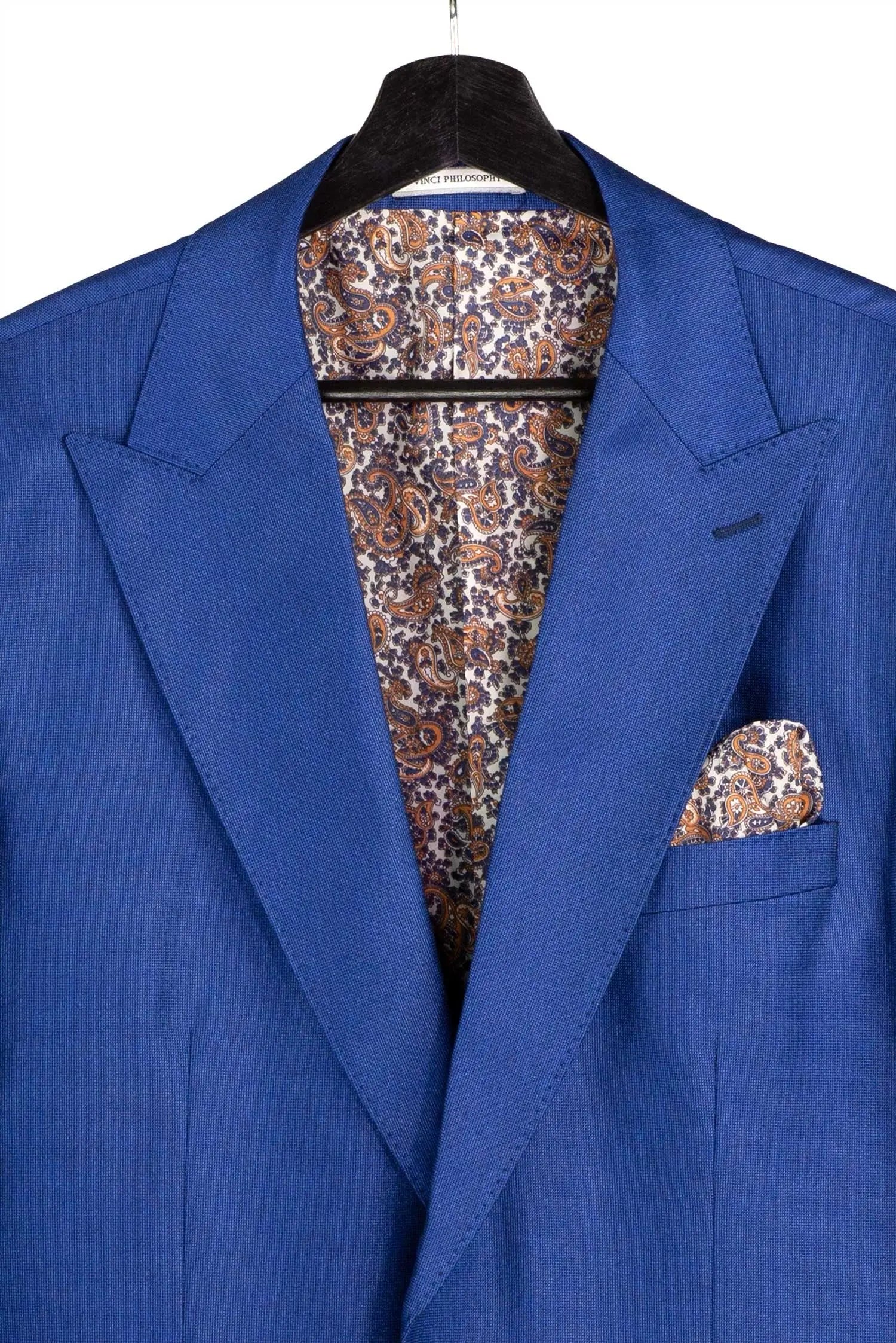 A royal blue suit jacket displayed on a black hanger, featuring a matching paisley patterned pocket square and matching patterned dress shirt visible inside the collar.