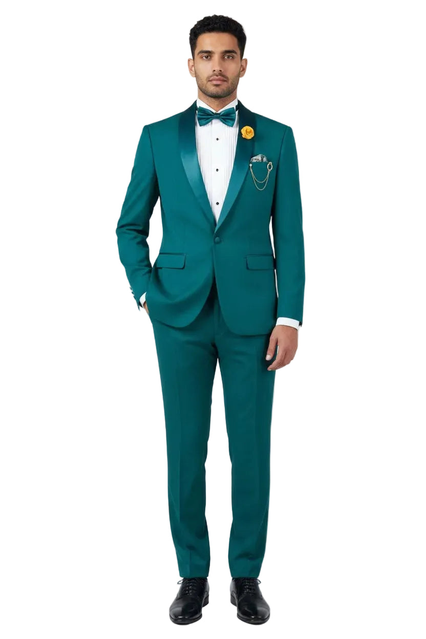 A man modeling a teal green tuxedo with satin lapels, a white dress shirt, a matching green bow tie, and a yellow flower boutonniere, standing against a light gray studio background.