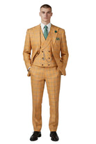 A man modeling a three-piece mustard yellow and orange plaid suit with a matching vest, white shirt, green tie, and green pocket square, standing against a light gray studio background.