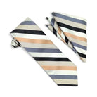 A striped necktie and matching pocket square set on a plain white background. The fabric features horizontal stripes in black, slate blue, cream, and a soft peach-beige color, with some stripes having a subtle textured dot pattern.