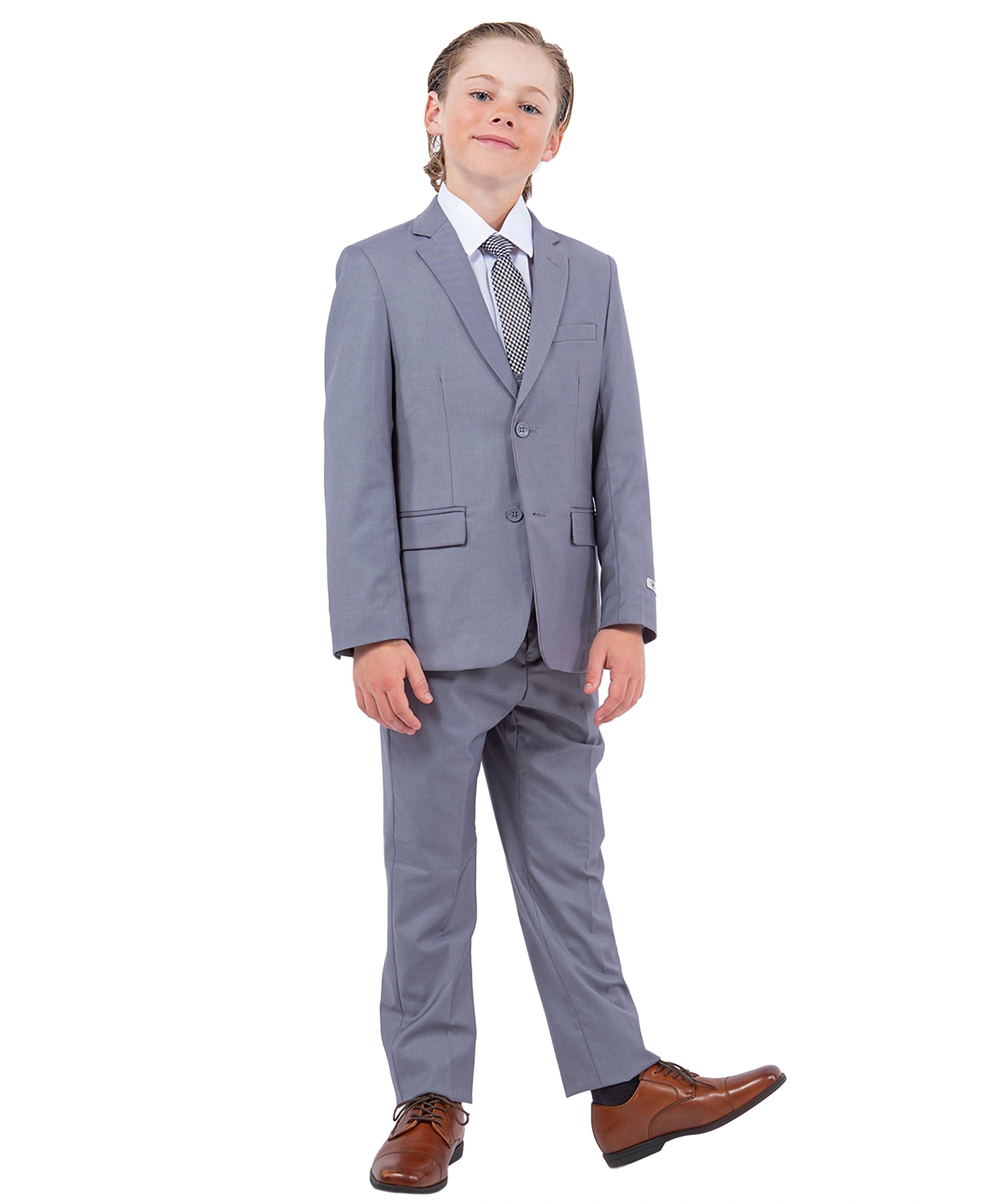 Child wearing a gray suit with a white shirt and brown shoes on a white background