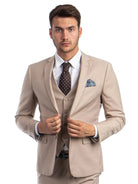 A man wearing a beige M & R Clothing skinny-fit 3-piece suit with a white shirt, brown patterned tie, and pocket square.