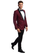A model wearing a M & R Clothing burgundy tuxedo jacket with a black satin shawl collar and slim-fit black trousers.