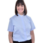 A woman wearing a light blue M & R Clothing short sleeve clergy shirt with a classic white tab collar.