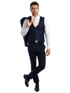 A man wearing a navy M & R Clothing skinny-fit 3-piece suit with a white shirt and patterned gold tie
